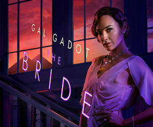 Gal Gadot 身穿紫色長裙，身後有霓虹新娘燈牌和日落山脈。 — 暮光 壁紙