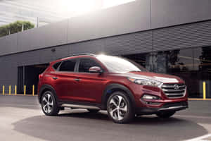 日落時分，紅色Hyundai Tucson SUV停在一棟現代建築前。 — Surface Pro 壁紙
