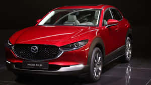 紅色Mazda CX-30 SUV展示在深色反光舞台上。 — 馬自達 壁紙