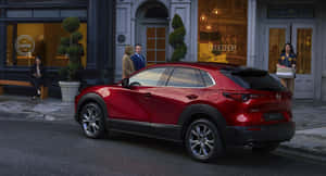 紅色Mazda CX-30 SUV停泊在靠近行人和商店的城市街道上。 — 馬自達 壁紙