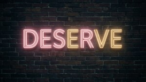 夜間在深色磚牆上顯示DESERVE的霓虹燈牌。