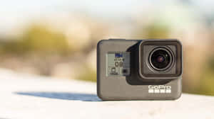 GoPro 攝影機在陽光明媚的戶外表面上，背景模糊。 — Studio Display 壁紙