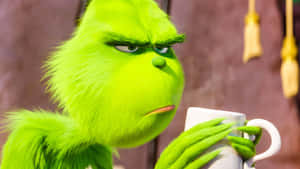 Grinch 拿著白色馬克杯，表情不悅 — 鬼靈精 壁紙