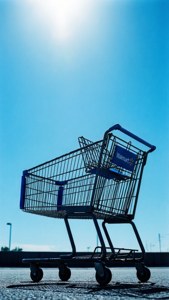 在明亮陽光下瀝青上的空Walmart購物車。