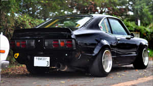 黑色經典日本跑車停在落葉滿地的林蔭街道上。 — 日產 Skyline GTR R34 壁紙