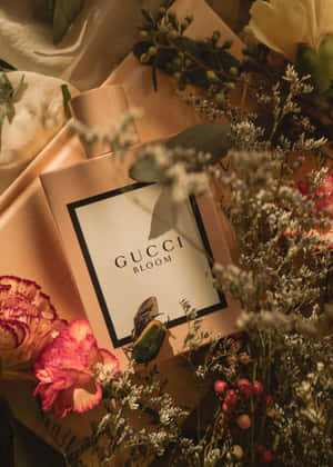 Gucci Bloom 香水瓶被新鮮和乾燥的花朵環繞在緞面表面上。 — IQOO Pad 壁紙