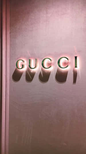 Gucci 標誌字母在帶有紋理的粉紅色牆壁上發光。 — 波西米亞美學 壁紙