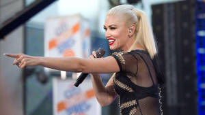 Gwen Stefani 在現場演唱會表演中唱歌並指向粉絲。 — 關·史蒂芬妮 壁紙