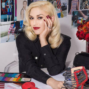 Gwen Stefani 在時尚工作室中，周圍環繞著設計材料和紅色配飾。 — 卡通鞋子 壁紙