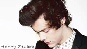 Harry Styles 身穿黑色西裝外套和圖案襯衫，捲髮向下看。 — 哈利·史泰爾斯 GIF 壁紙