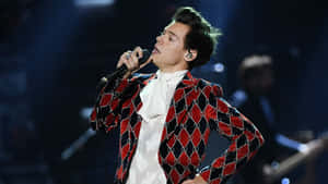 Harry Styles 穿著紅黑圖案外套在舞台上表演。 — 哈利波特 筆電 壁紙