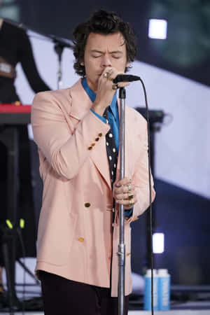 Harry Styles 在舞台上穿著粉紅色西裝外套和波點襯衫唱歌。 — 哈利·史泰爾斯 GIF 壁紙