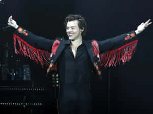 Harry Styles 身穿黑色西裝，搭配紅色流蘇和花卉刺繡，在舞台上表演。 — 哈利·史泰爾斯 GIF 壁紙