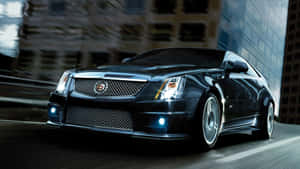黑色Cadillac CTS-V在夜晚穿過城市，帶有發光的車頭燈。 — 凱迪拉克 壁紙
