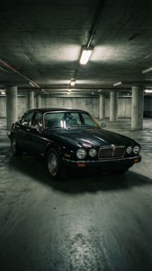 黑色捷豹轎車停在光線昏暗的混凝土地下車庫中。