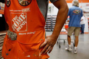身穿橙色圍裙的 Home Depot 工人在商店通道中拿著工具。 — 好市多 壁紙