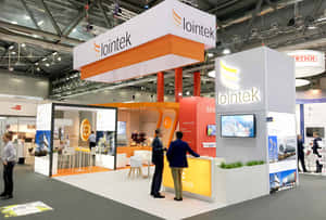 會議中心內的 Iointek 貿易展攤位，設有參觀者和數碼顯示屏。 — 雕塑 壁紙