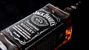 Jack Daniel's 威士忌酒瓶，琥珀色液體在黑暗背景下發光。 — 品牌 壁紙