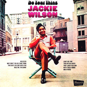 Jackie Wilson 坐在城市街道的導演椅上，對著鏡頭微笑。 — 傑基·羅賓森 壁紙
