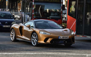 金色McLaren跑車在紅色巴士附近的城市交通中行駛。 — Steam Deck 壁紙