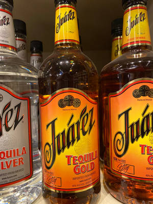Juárez 龍舌蘭酒瓶以透明和金色品種陳列在商店貨架上。 — 3:4 壁紙