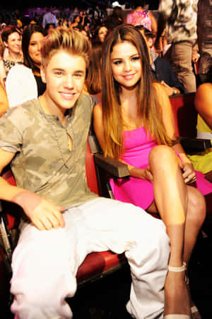 Justin Bieber 和 Selena Gomez 在公開活動中一起坐著微笑。 — Huawei MatePad Air (2025) 壁紙