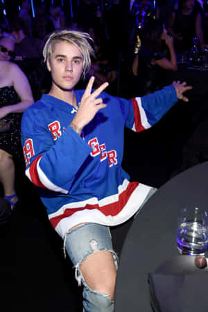 Justin Bieber 在派對上穿著冰球球衣做出和平手勢。 — 小米平板 8 壁紙