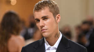 Justin Bieber 身穿黑色西裝和白色襯衫，在活動中表情嚴肅。 — 小賈斯汀 壁紙