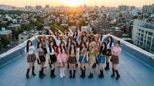 K-pop女團在日落時於屋頂擺姿勢，背後是城市天際線。