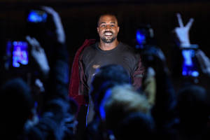 Kanye West 在演唱會上微笑，粉絲舉起手機。 — 肯伊·威斯特 壁紙