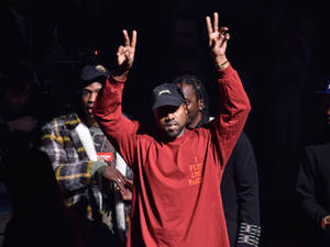 Kanye West 在現場活動中穿著紅色衛衣和黑色帽子做出和平手勢。 — 肯伊·威斯特 壁紙
