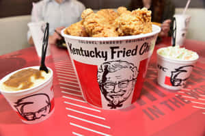 KFC 炸雞桶配配菜放在品牌桌上。 — 肯德基 壁紙