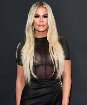 Khloé Kardashian 在活動中穿著帶有金色胸罩的黑色透視連衣裙。