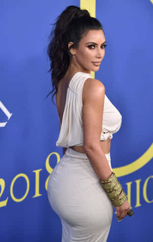 Kim Kardashian 在2018年活動中穿著白色服裝，背景為藍色和金色。 — Pixel Tablet 壁紙