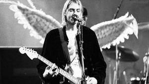 Kurt Cobain 在現場演唱會中帶著天使翅膀彈吉他。 — 涅槃 壁紙