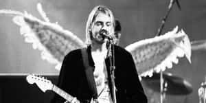Kurt Cobain 身後有天使翅膀，對著麥克風唱歌。 — 涅槃 壁紙