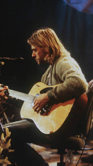 Kurt Cobain 在聚光燈下於舞台上彈奏木吉他。 — 涅槃 壁紙
