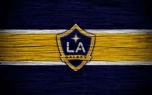 LA Galaxy 足球隊標誌，黃藍條紋木質背景。 — 洛杉磯 壁紙