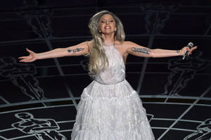 Lady Gaga 身穿白色長袍在舞台上表演，雙臂伸展。 — 女神卡卡 壁紙