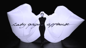 Lady Gaga 身穿黑色緊身連衣褲，巨大的白色充氣手拼出她的名字。 — 女神卡卡 壁紙