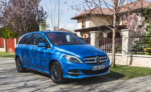 藍色 Mercedes-Benz 旅行車停放在櫻花盛開的房子前。 — Steam Deck OLED 壁紙