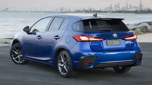 藍色Lexus CT 200h停在日落時分的海濱附近，有城市天際線。 — 凌志 壁紙