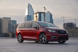 紅色Chrysler Pacifica小型貨車在屋頂俯瞰有建築起重機的城市。 — Surface Pro 壁紙
