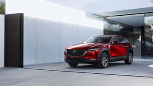 紅色Mazda CX-30 SUV停在一棟現代玻璃建築前。 — 馬自達 壁紙