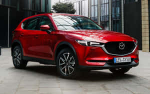 紅色Mazda CX-5 SUV停放在玻璃建築附近的石頭廣場上。 — 馬自達 壁紙