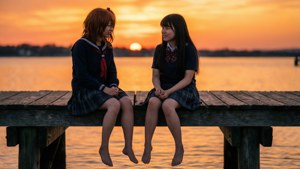 兩名身穿校服的動漫女孩赤腳坐在碼頭上，夕陽西下。