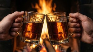 兩隻手在壁爐前用啤酒杯碰杯