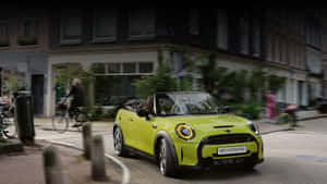 萊姆綠色MINI Convertible在歐洲城市街道上行駛，有自行車騎士。 — 霓虹車 壁紙
