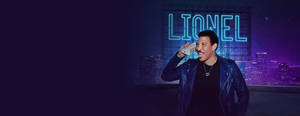 Lionel Richie 在天臺上微笑，身後有霓虹燈標誌。 — 音樂 壁紙