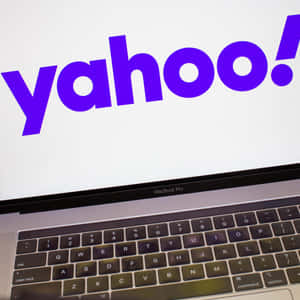 MacBook Pro 在螢幕上顯示 Yahoo 標誌，鍵盤可見。 — 雅虎 壁紙